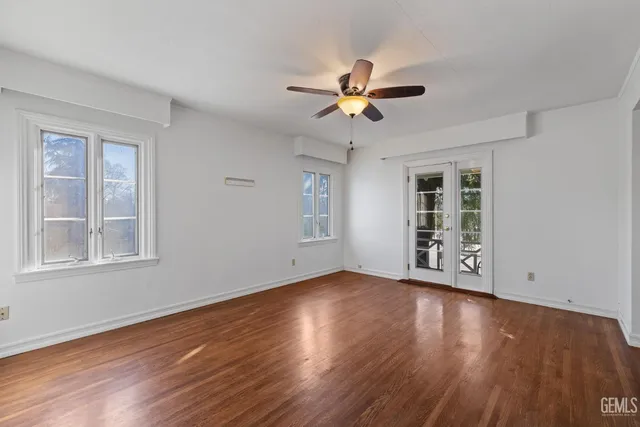 a view of an empty room with wooden floor and a window