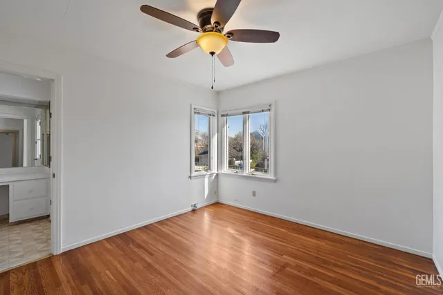 a view of an empty room with window and wooden floor