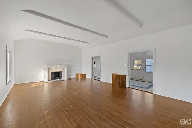 a view of empty room with wooden floor and fireplace