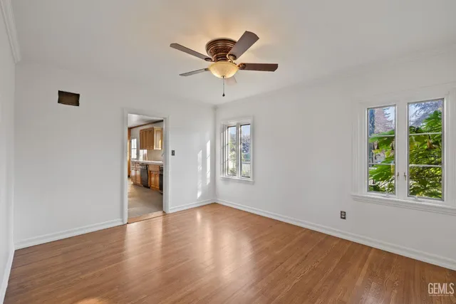 a view of empty room with wooden floor and fan