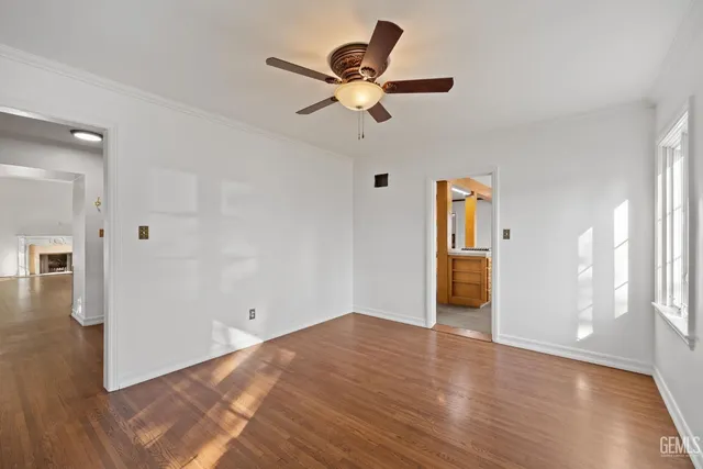 a view of empty room with wooden floor and ceiling fan