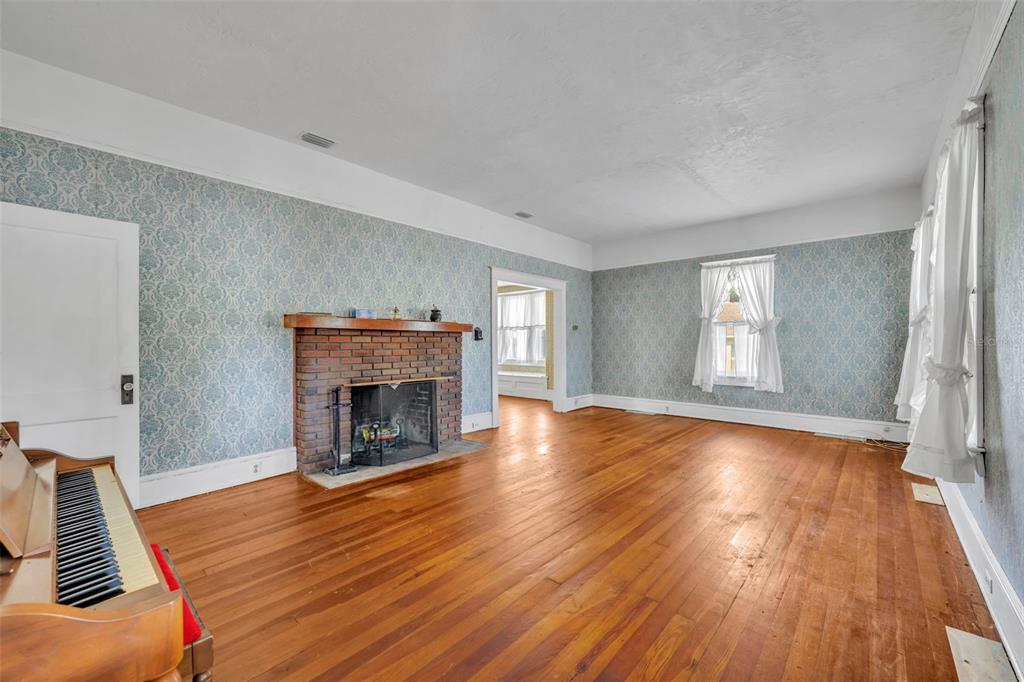 207 Perkins Street Leesburg, FL 34748 - Photo 5 of 31 an empty room with wooden floor fireplace and windows