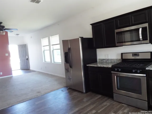 a kitchen with granite countertop a refrigerator stove and microwave