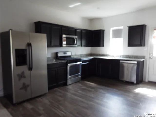 a kitchen with stainless steel appliances a sink a stove a microwave a refrigerator a sink and dishwasher