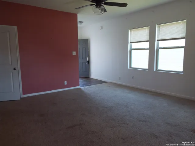 an empty room with a window and a ceiling fan