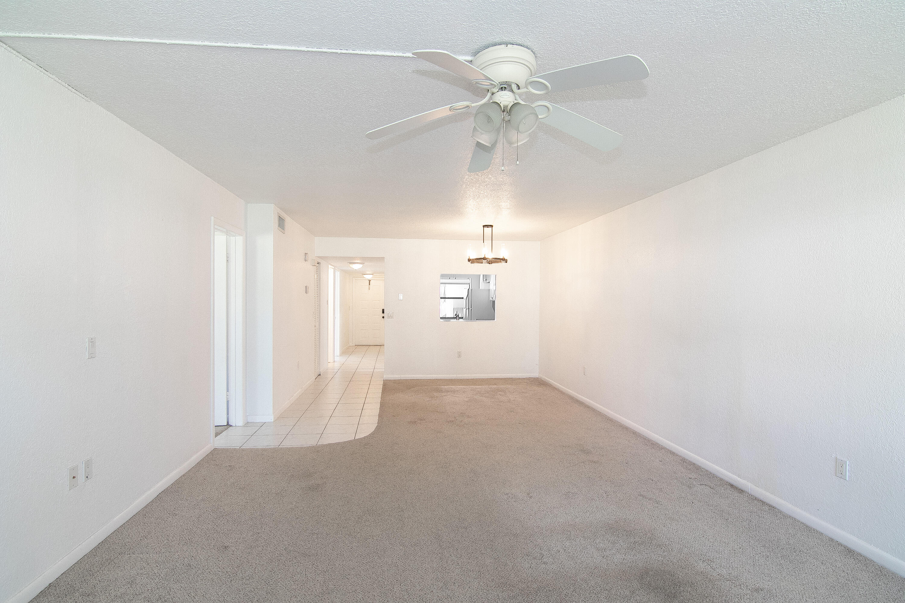 3130 Southwest 20th Terrace, Unit 13B1 Delray Beach, FL 33445 - Photo 14 of 47 an empty room with chandelier fan and windows