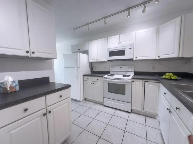 a kitchen with granite countertop a sink a stove and cabinets