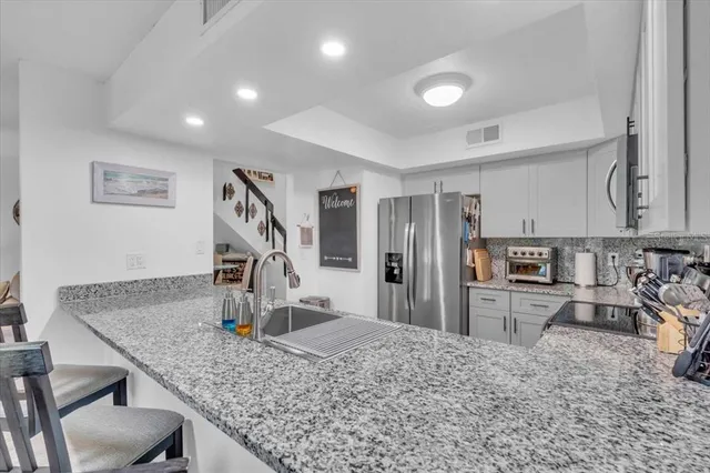 a kitchen with stainless steel appliances granite countertop a sink a stove a refrigerator a microwave oven with granite countertops and cabinets