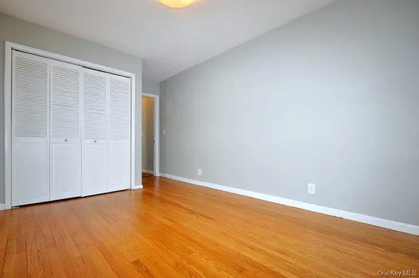 a view of an empty room with wooden floor and closet