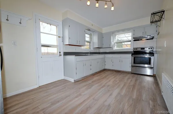 a kitchen with granite countertop white cabinets and wooden floor