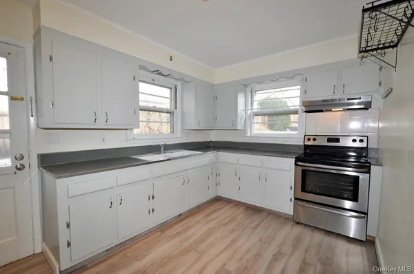 a kitchen with granite countertop white cabinets appliances and a window