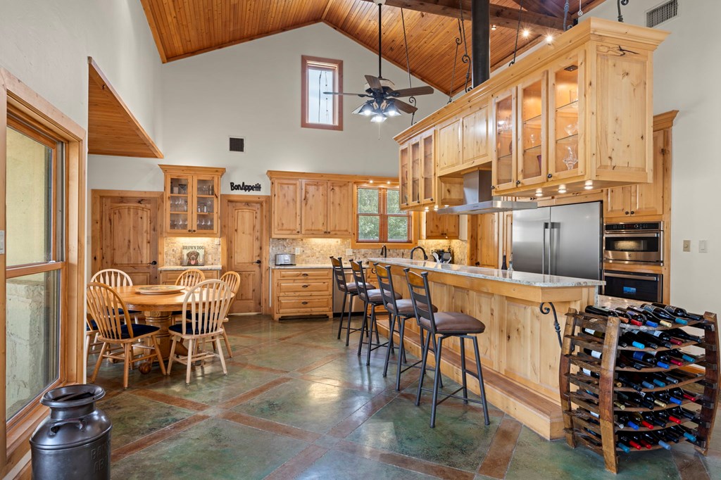 2320 Fiedler Road Harper, TX 78631 - Photo 12 of 62 a kitchen with stainless steel appliances kitchen island granite countertop a table chairs and a refrigerator