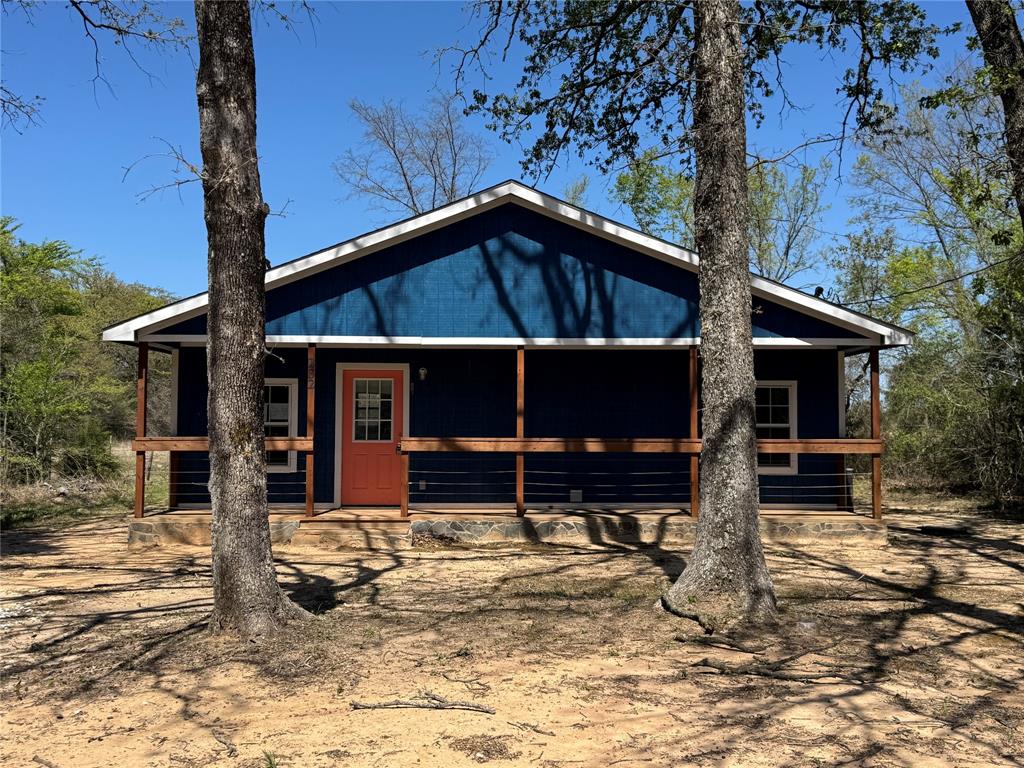 232 West Quanah Road Mabank, TX 75156 - Photo 1 of 13 Exterior featuring blue siding, white trim, a covered porch with natural wood railings, and an orange front door
