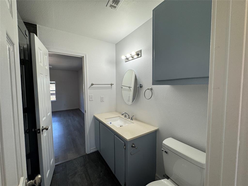232 West Quanah Road Mabank, TX 75156 - Photo 11 of 13 Bathroom vanity with blue cabinetry, a light-toned countertop, and an oval mirror