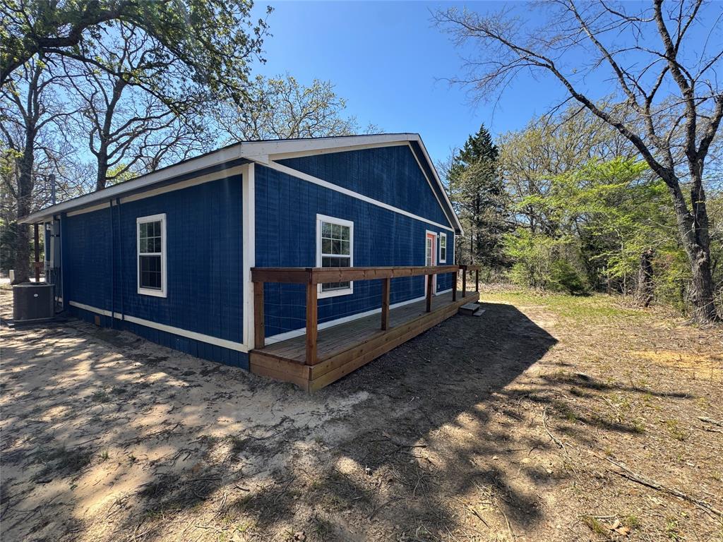 232 West Quanah Road Mabank, TX 75156 - Photo 13 of 13 Exterior featuring rich blue siding with white trim, a wooden deck with railing, and multiple double-hung windows