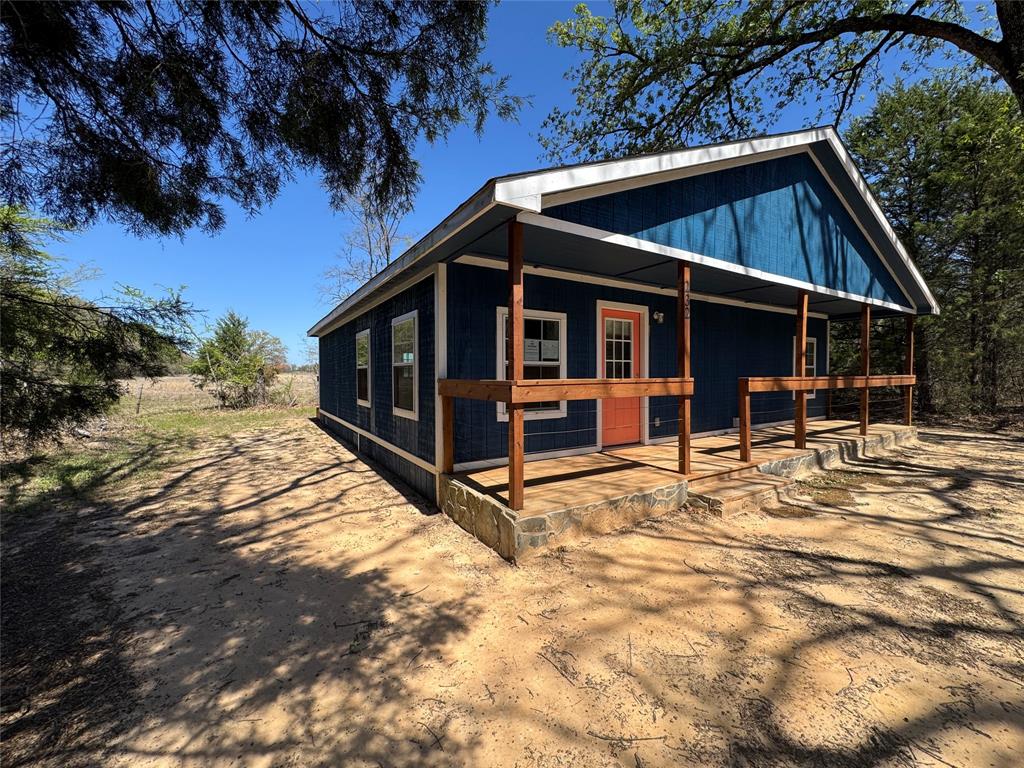 232 West Quanah Road Mabank, TX 75156 - Photo 3 of 13 Blue exterior with a gable roofline, featuring a covered porch with wooden posts and railings
