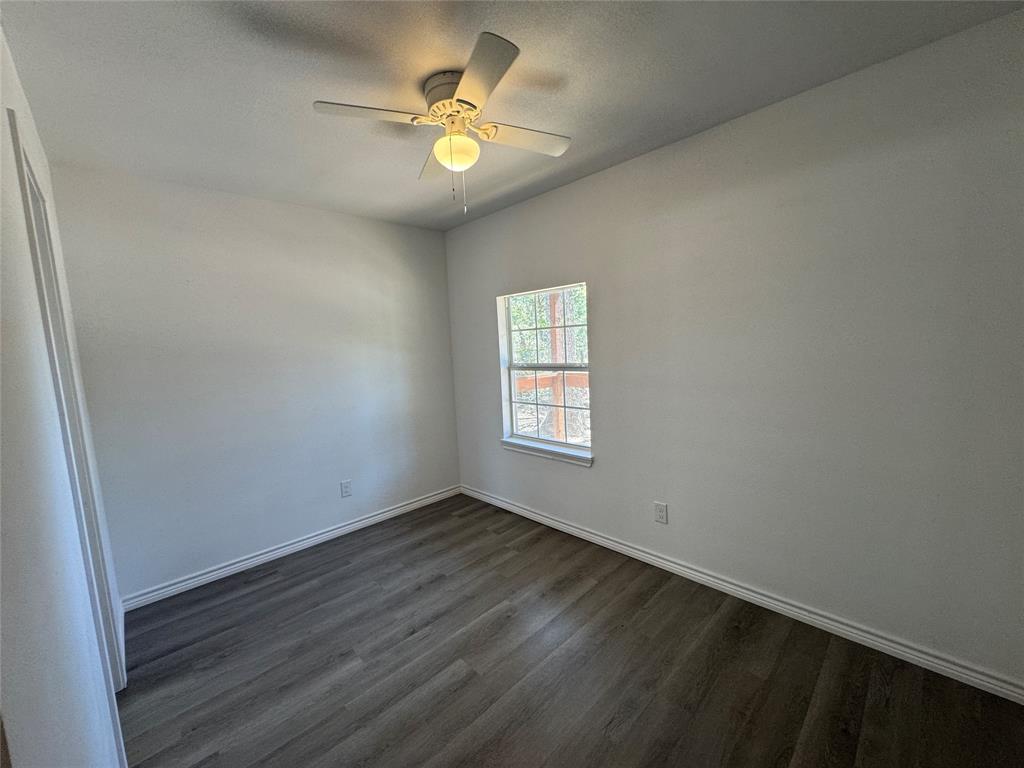 232 West Quanah Road Mabank, TX 75156 - Photo 10 of 13 Room featuring wood-finish flooring, white walls, and a ceiling fan with integrated lighting