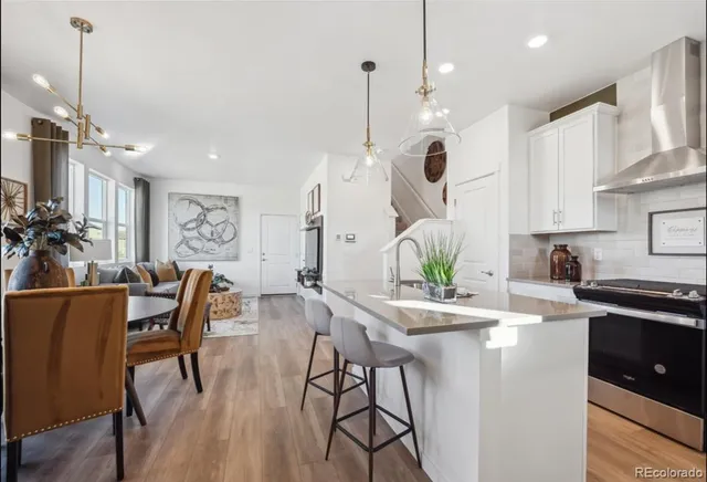 a kitchen with stainless steel appliances kitchen island granite countertop a dining table chairs and white cabinets