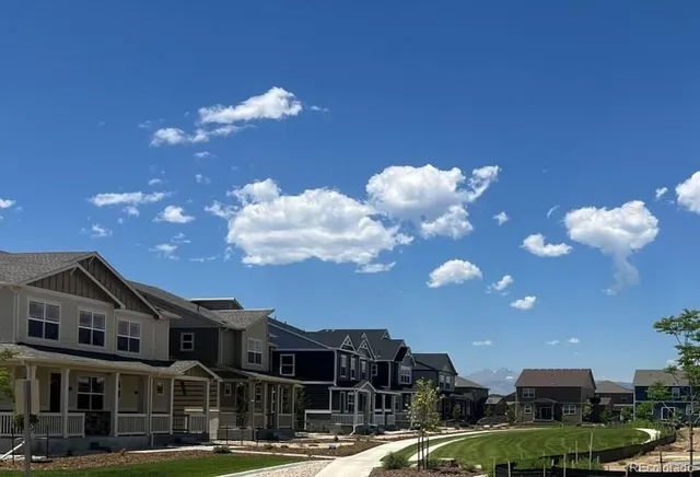 a front view of a building with lot of cars and trees
