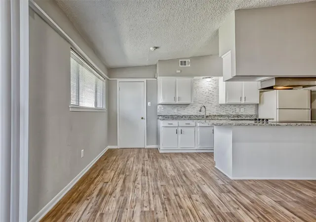 a kitchen with granite countertop white cabinets and wooden floor