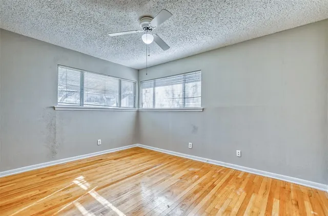 a view of an empty room with wooden floor and a bathroom