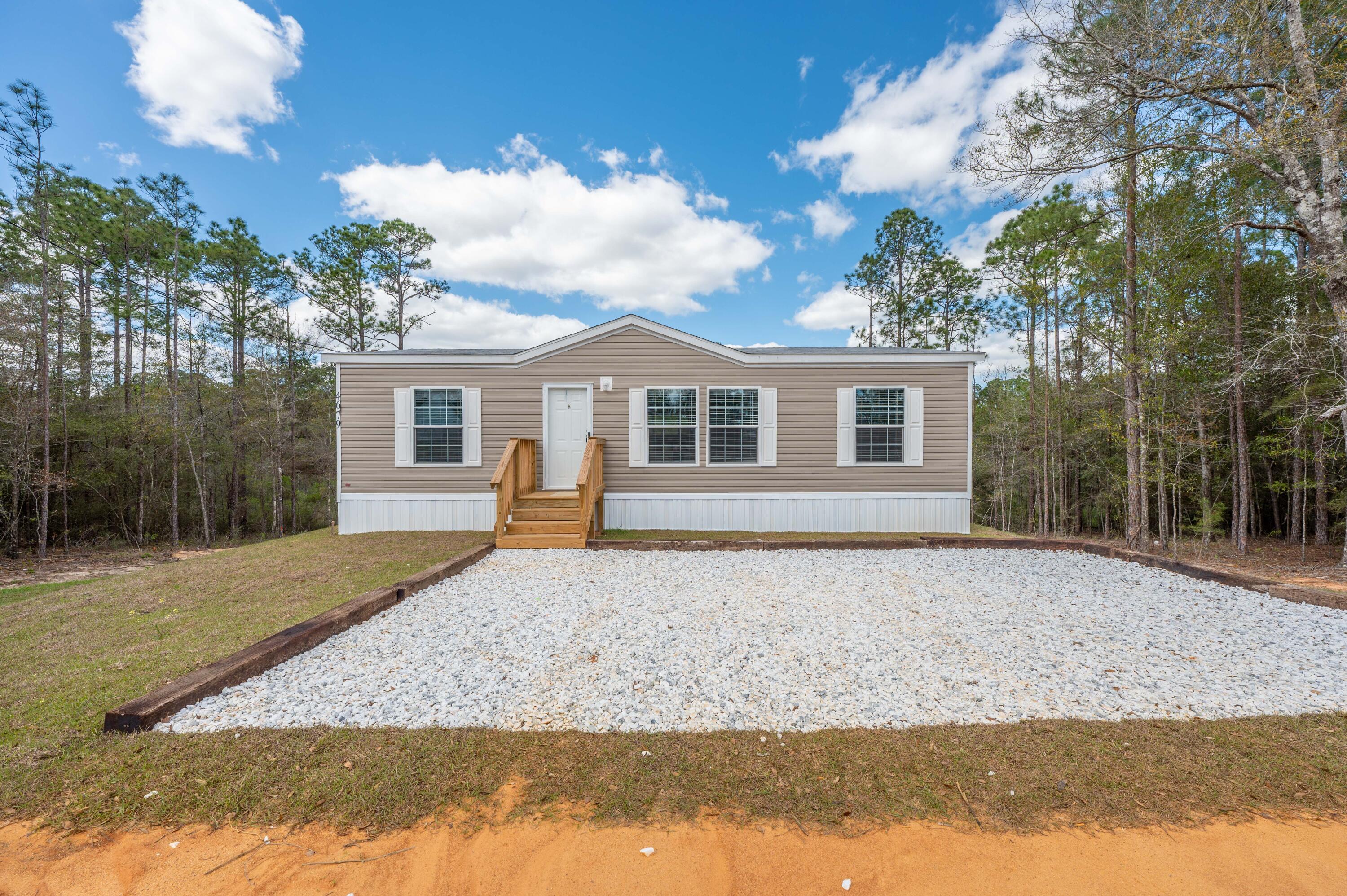 4679 Dove Way Crestview, FL 32539 - Photo 3 of 41 a front view of a house with a garden and trees