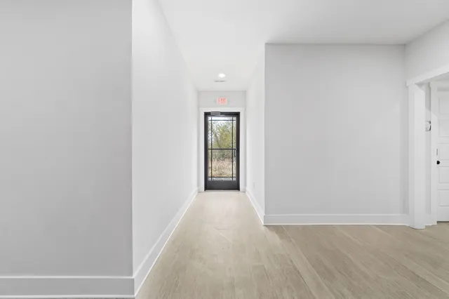 a view of a hallway with wooden floor and a window