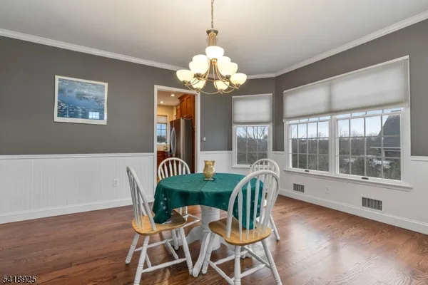 a dining room with wooden floor a chandelier a glass table and chairs