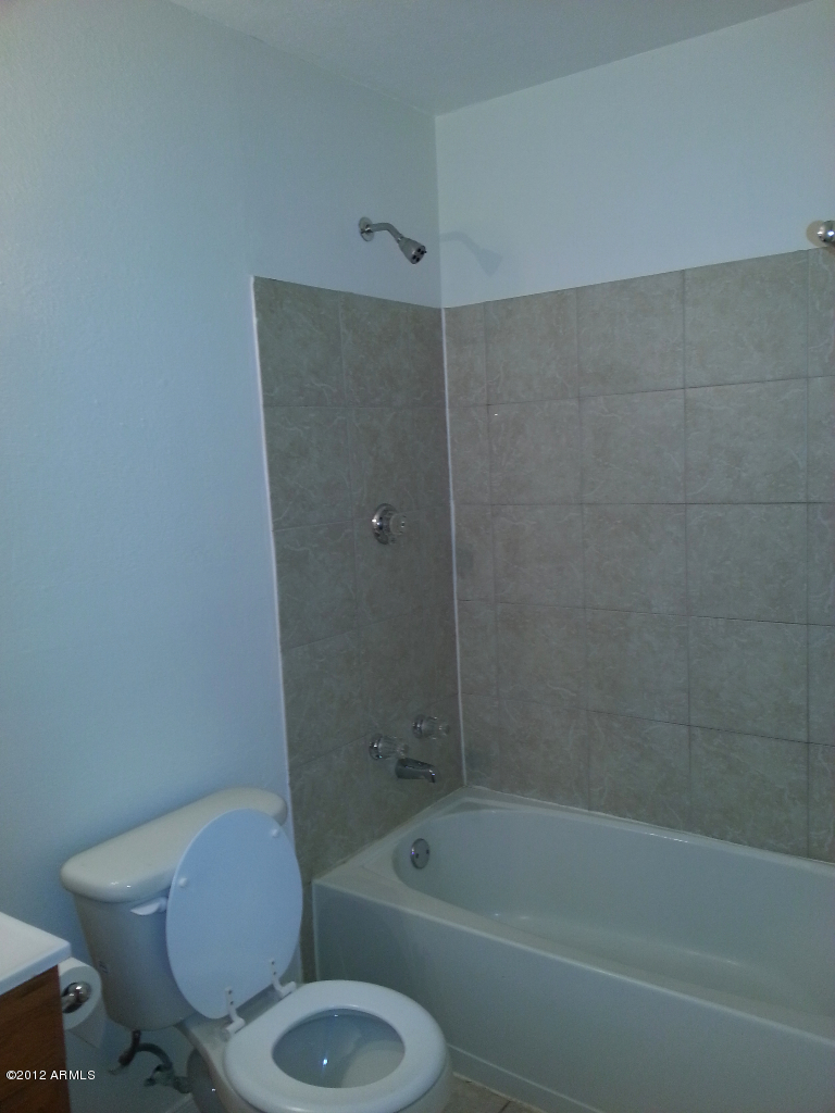 3043 West Bloomfield Road Phoenix, AZ 85029 - Photo 11 of 18 a white toilet and tub sitting next to a bathroom sink