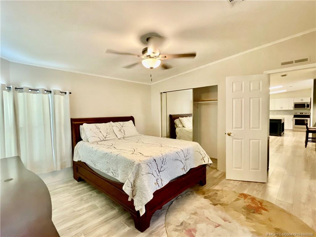 16398 Southwest Two Wood Way Indiantown, FL 34956 - Photo 11 of 24 a bedroom with a bed and a chandelier