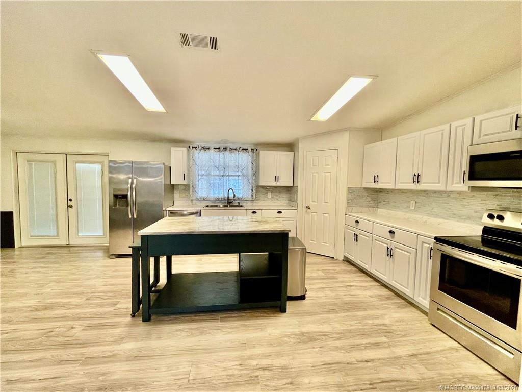 16398 Southwest Two Wood Way Indiantown, FL 34956 - Photo 5 of 24 a kitchen with stainless steel appliances granite countertop a stove a sink and a microwave