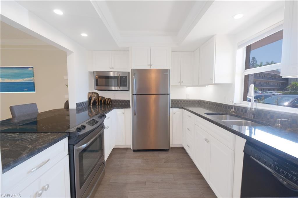 5499 Rattlesnake Hammock Road, Unit A105 Naples, FL 34113 - Photo 2 of 23 Kitchen with appliances with stainless steel finishes, a tray ceiling, white cabinets, and sink