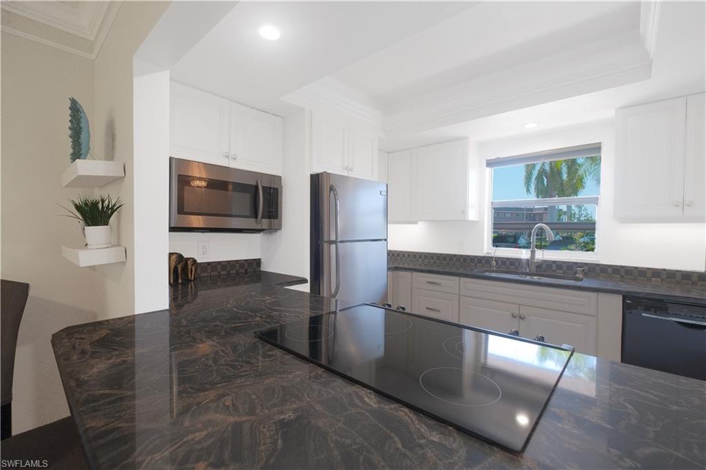 5499 Rattlesnake Hammock Road, Unit A105 Naples, FL 34113 - Photo 3 of 23 Kitchen with stainless steel appliances, sink, a tray ceiling, and white cabinets