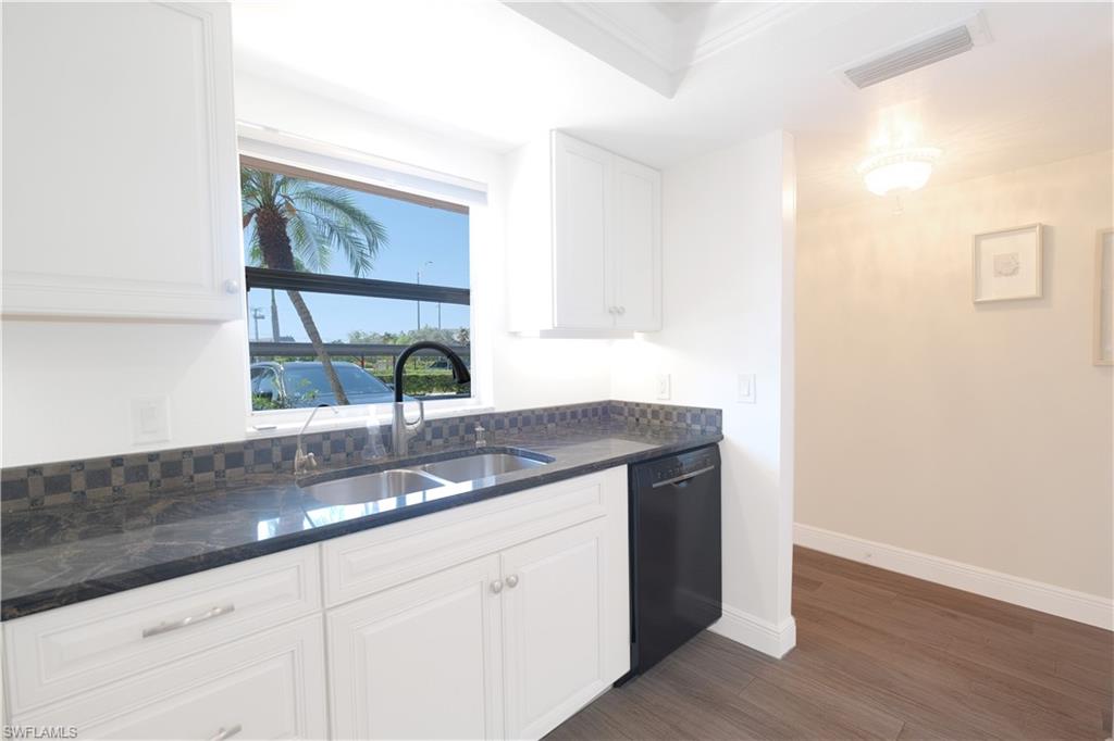 5499 Rattlesnake Hammock Road, Unit A105 Naples, FL 34113 - Photo 6 of 23 Kitchen featuring tasteful backsplash, dishwasher, dark wood-type flooring, sink, and white cabinetry