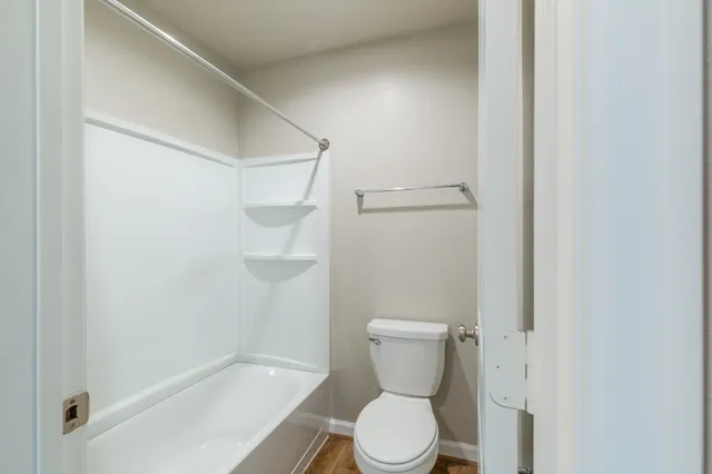 a white toilet sitting next to a bath tub