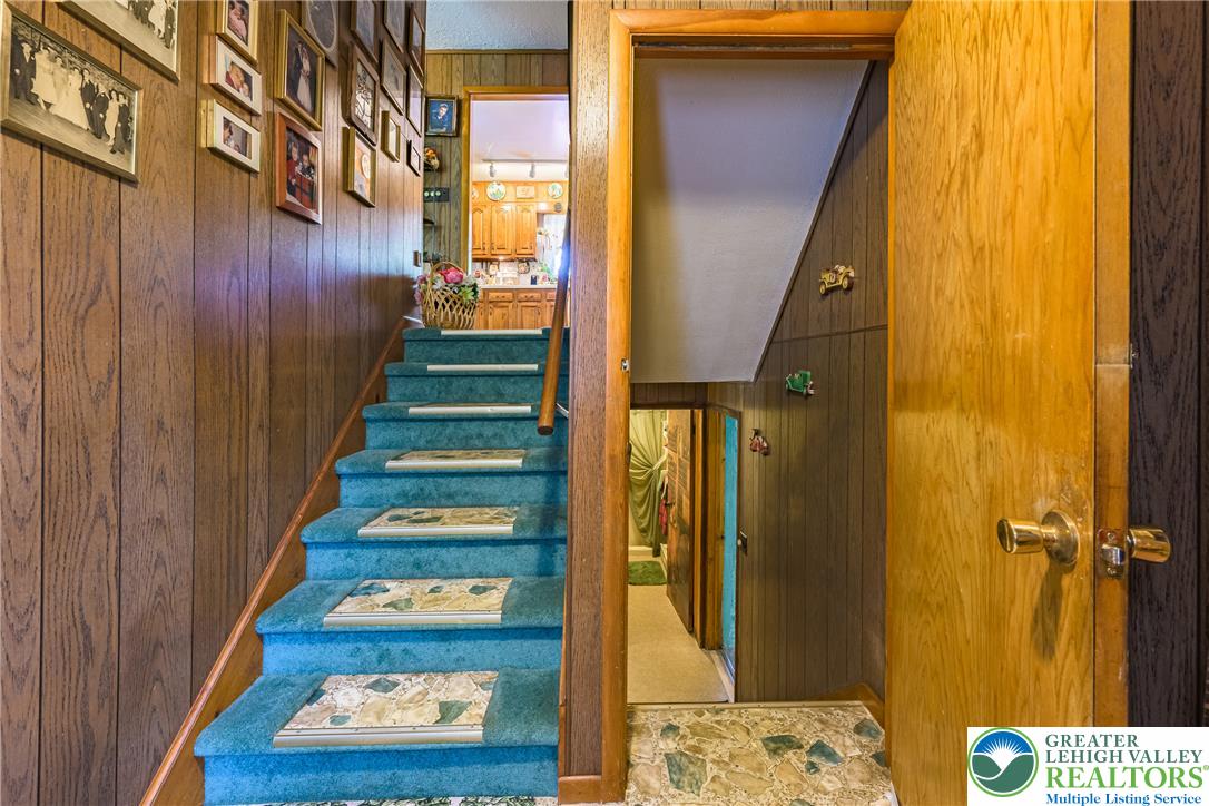 678 Interchange Road Kresgeville, PA 18333 - Photo 32 of 45 A split-level home with wood paneling and teal carpeted stairs leading to a glimpse of the kitchen.
