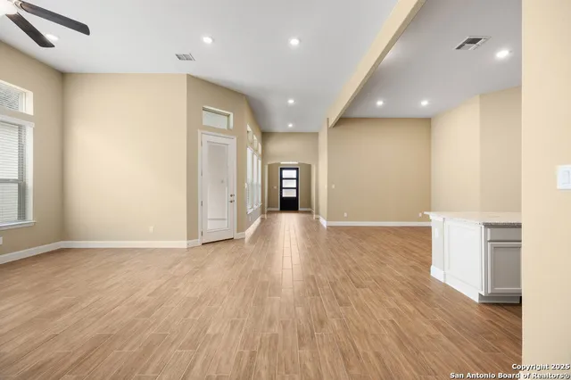 an empty room with wooden floor and entrance to ceiling window