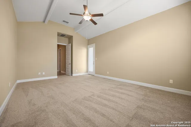 an empty room with a ceiling fan and carpet