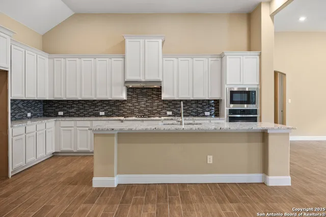 a kitchen with stainless steel appliances granite countertop a stove a sink and white cabinets
