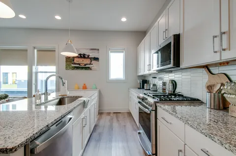 a kitchen with stainless steel appliances granite countertop a sink stove and refrigerator