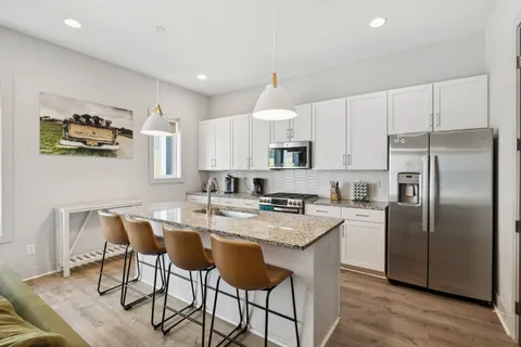 a kitchen with stainless steel appliances a white refrigerator a sink a stove a dining table and chairs