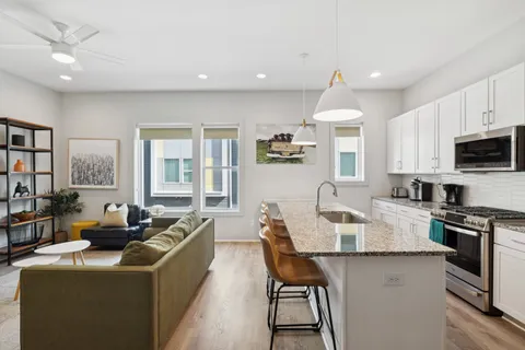 a living room with stainless steel appliances kitchen island granite countertop a dining table chairs refrigerator and cabinets