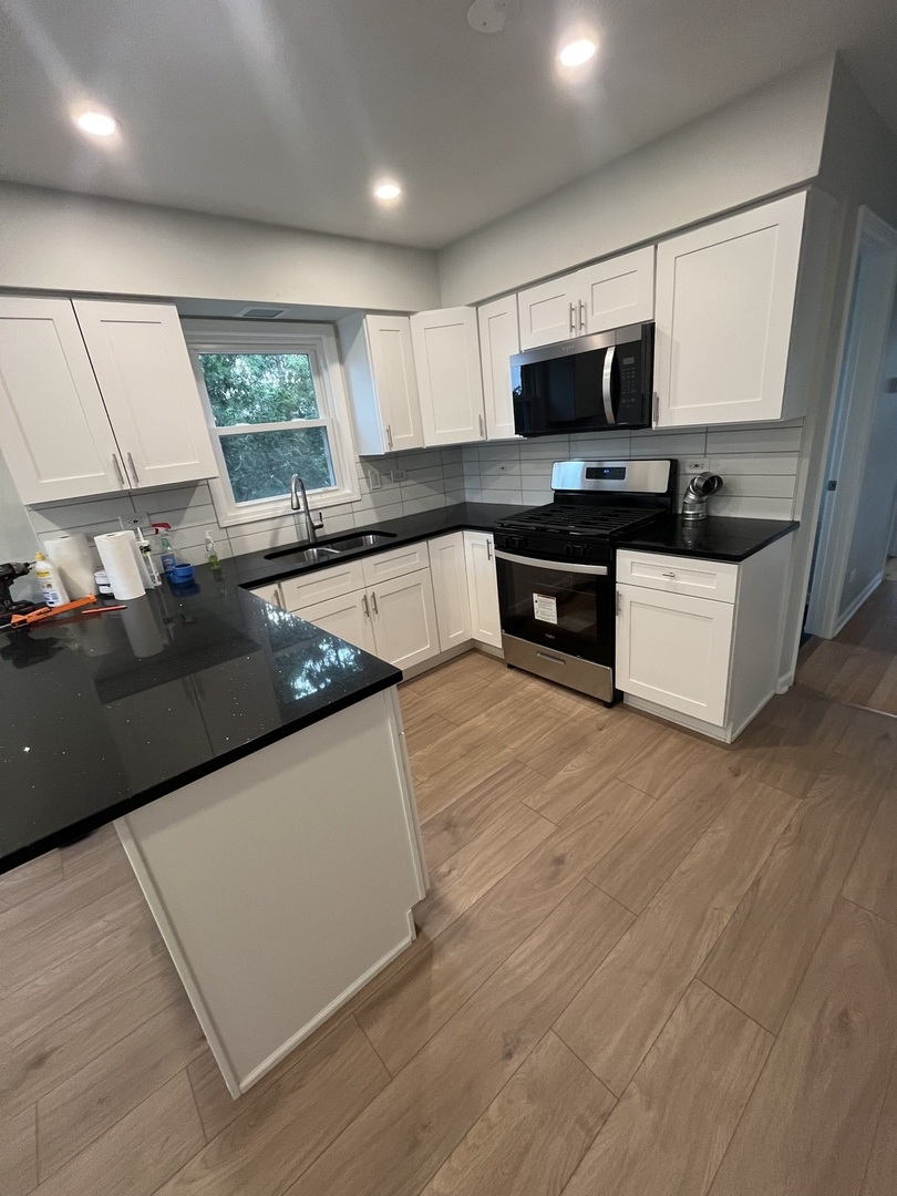4543 West Marquette Road, Unit 2 Chicago, IL 60629 - Photo 8 of 12 a large kitchen with stainless steel appliances a large counter top a stove a microwave a sink and a refrigerator