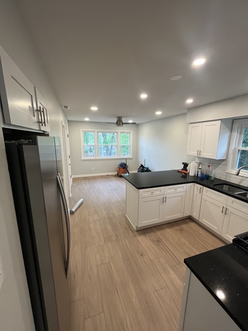 4543 West Marquette Road, Unit 2 Chicago, IL 60629 - Photo 9 of 12 a large white kitchen with stainless steel appliances granite countertop a refrigerator a sink a stove and white cabinets with wooden floor