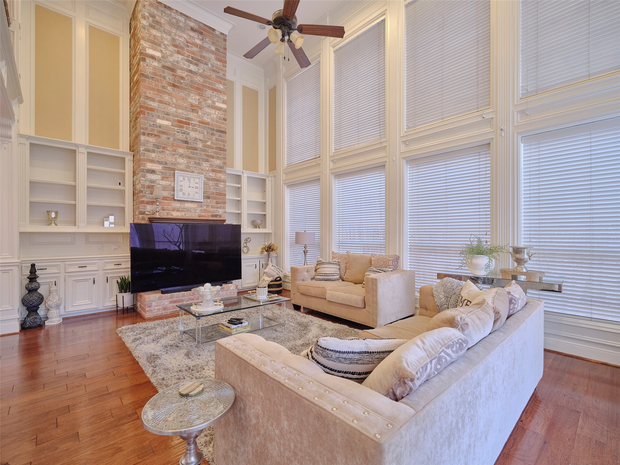16623 Manningtree Lane Spring, TX 77379 - Photo 2 of 39 This spacious living room features high ceilings and abundant natural light from large windows. The modern fireplace with a brick accent wall, built-in shelving, superior hardwood floors and neutral colors create an inviting ambiance.