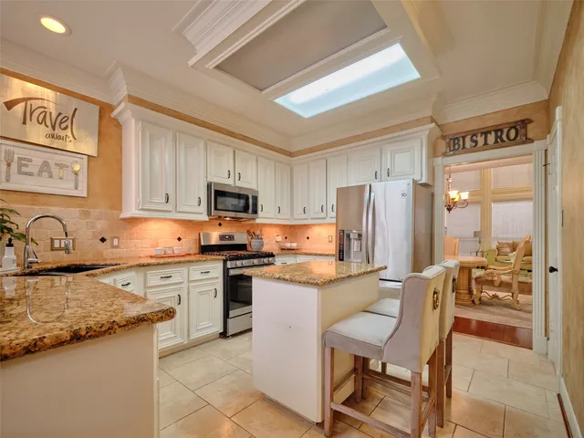 a kitchen with stainless steel appliances granite countertop a stove top oven a sink refrigerator and a granite counter tops