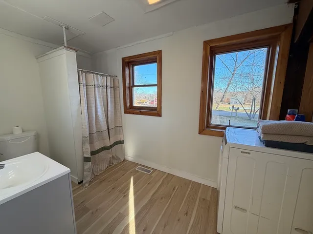 a view of hallway with window and wooden floor