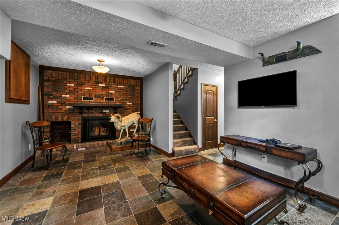 5704 McCartney Road Sandusky, OH 44870 - Photo 45 of 50 Living area featuring stairs, stone tile floors, a textured ceiling, and a fireplace
