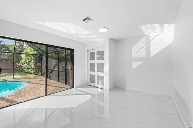 a view of an empty room with a window and hardwood floor