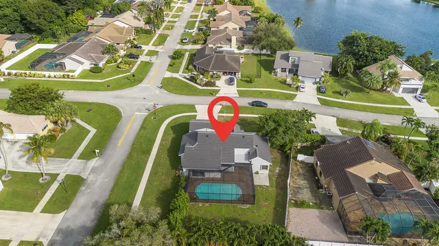 an aerial view of a swimming pool with a yard and plants